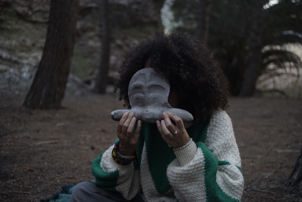 a person holding a ceramic instrument which is also a mask